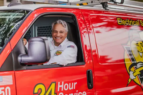 Mister Sparky Electrician Tech, Mike, looking out his window smiling at the camera